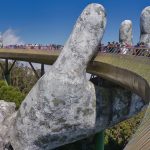 The iconic Golden Bridge with giant hand sculptures at Ba Na Hills, Vietnam, under a clear blue sky.